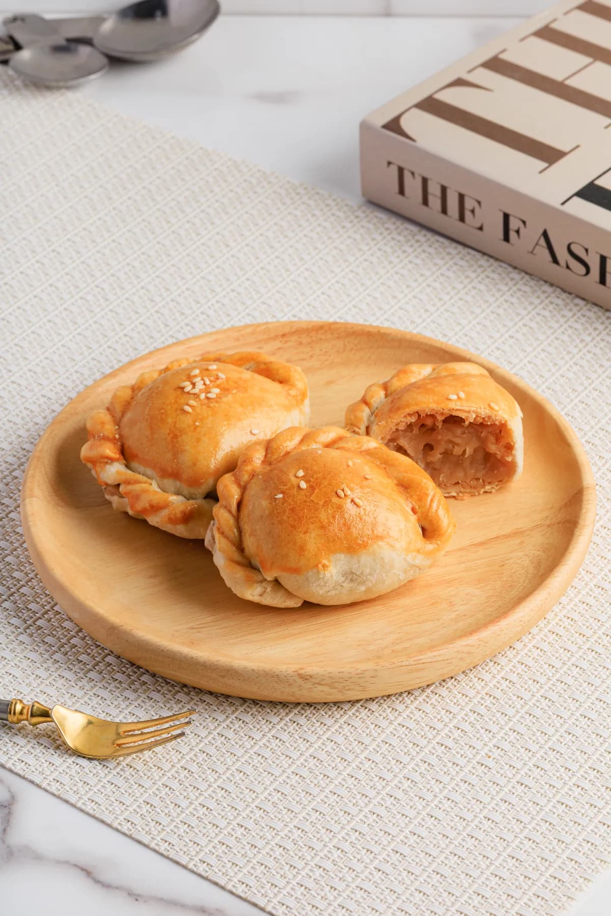 Golden mini pies on a wooden plate with a woven placemat.